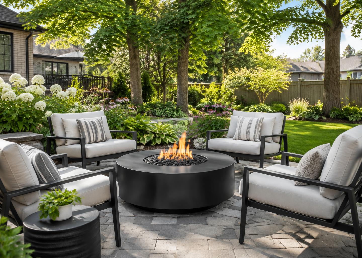 Round gas fire table with lounge chairs among mature trees and flowers